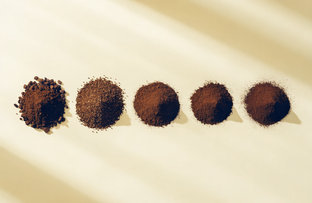 Five piles of coffee grounds arranged from coarse to fine, showing the espresso grind size progression