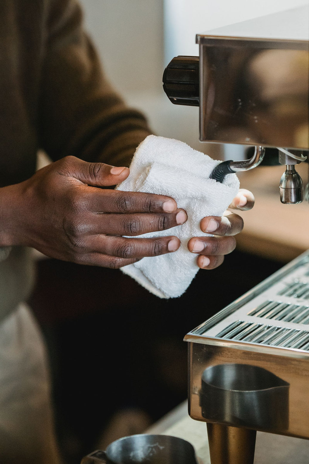 Barista wiping down an espresso machine with a soft cloth