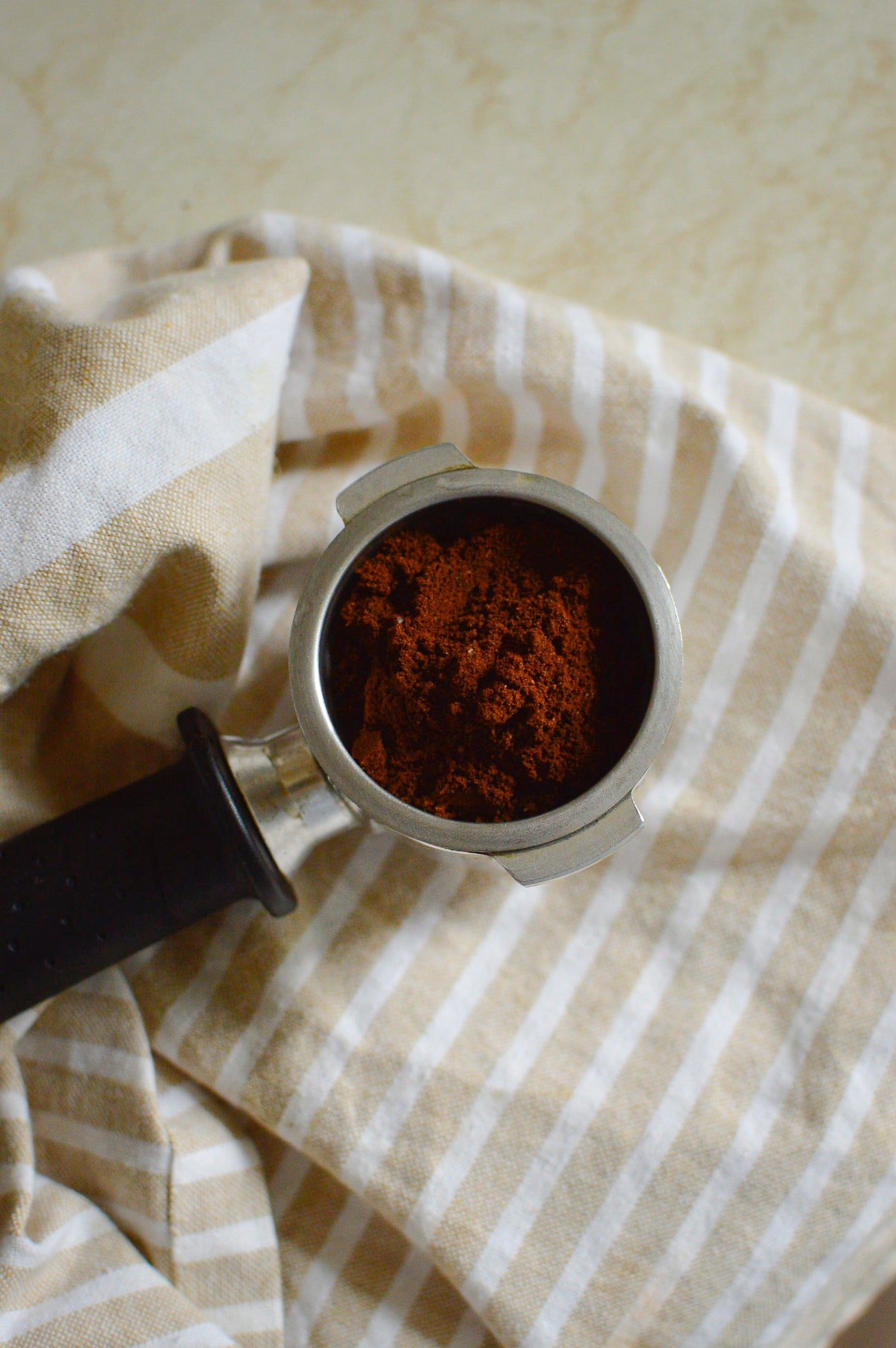 Loose coffee grounds in a portafilter basket before stirring and tamping