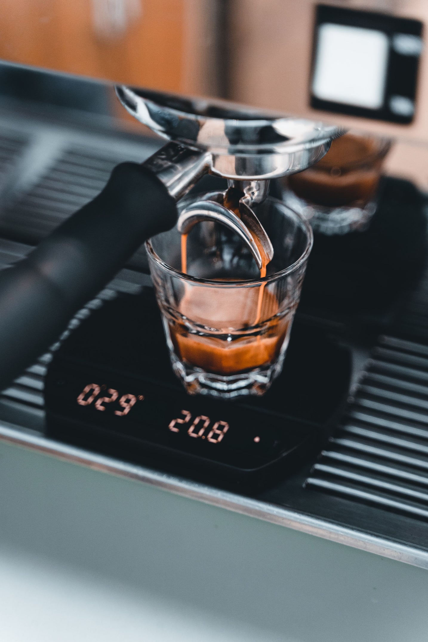Espresso extracting from a portafilter into a glass on a scale mid-shot
