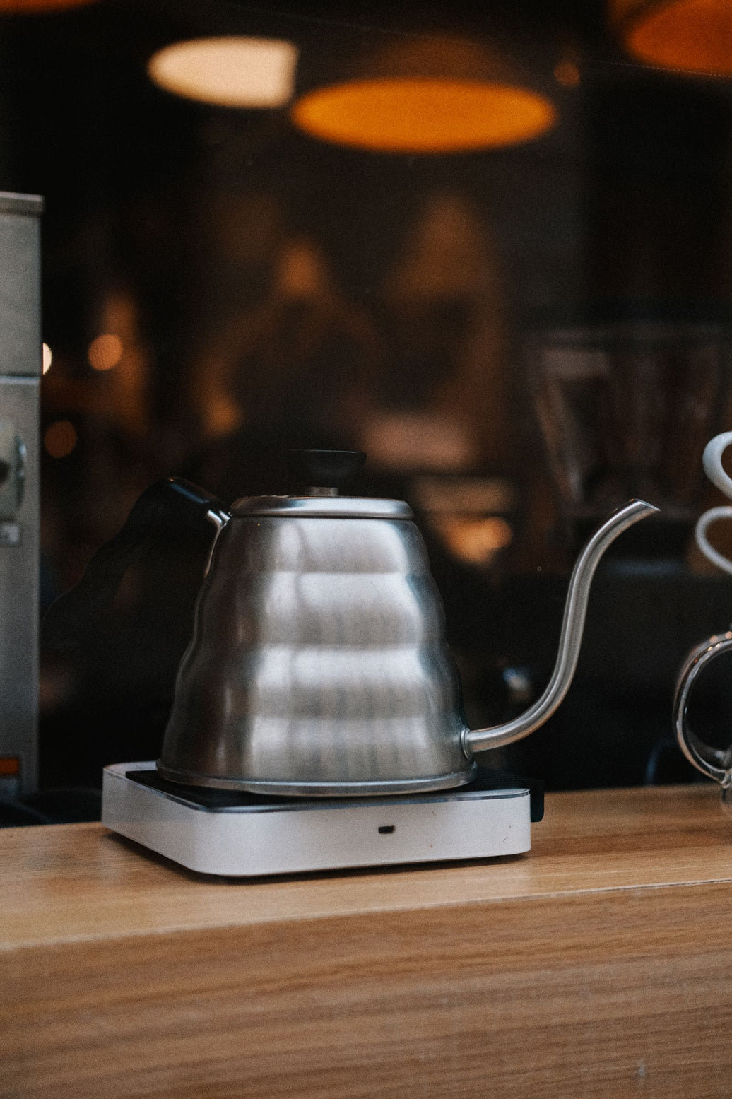 Stainless steel gooseneck kettle resting on a warm wooden kitchen counter