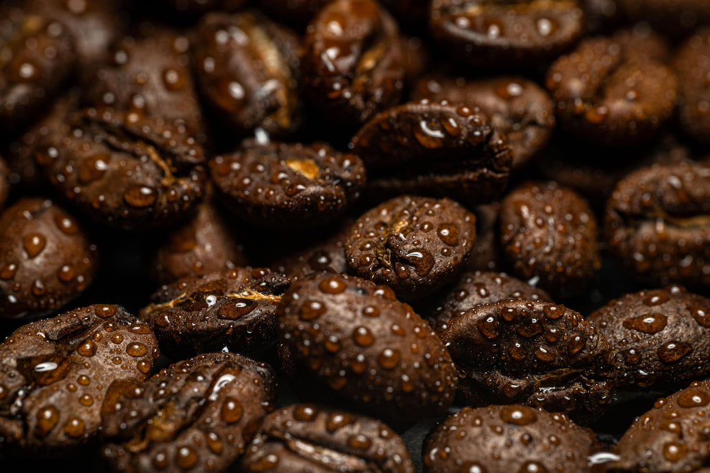 Macro close-up of roasted coffee beans with small water droplets on their surface
