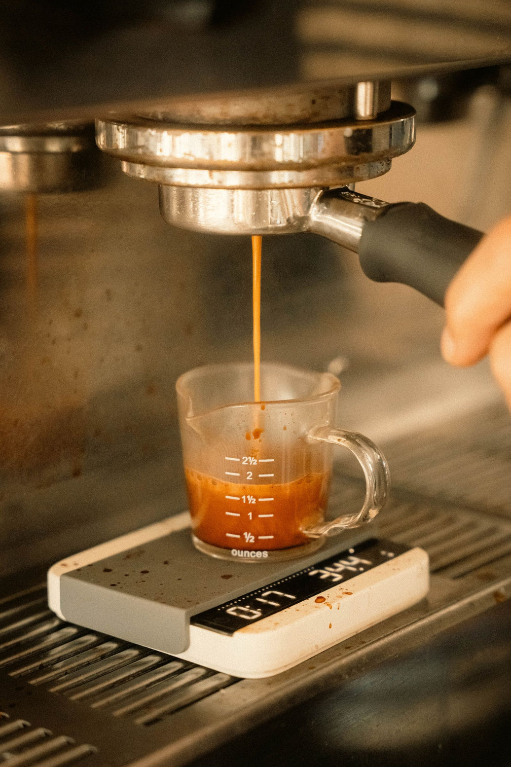 Espresso pouring into a measuring cup on a digital coffee scale