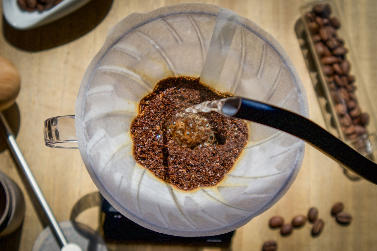Overhead view of hot water being poured over fresh coffee grounds in a pour over brewer