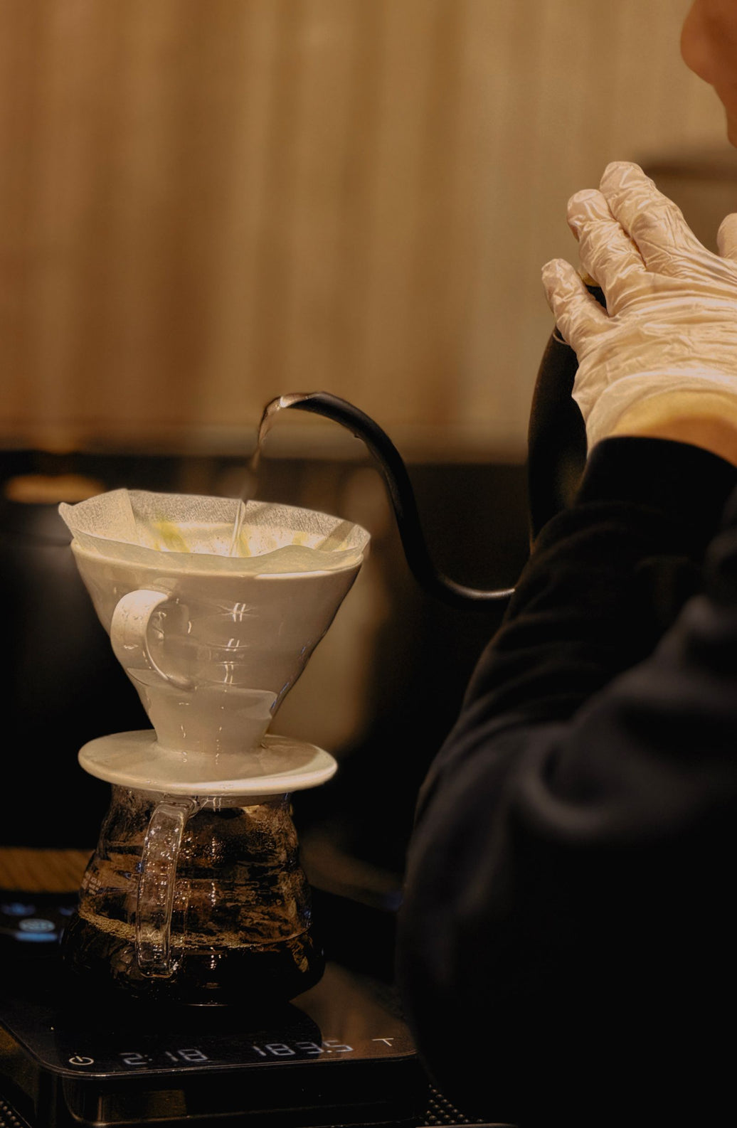 Barista carefully pouring hot water through a V60 cone dripper