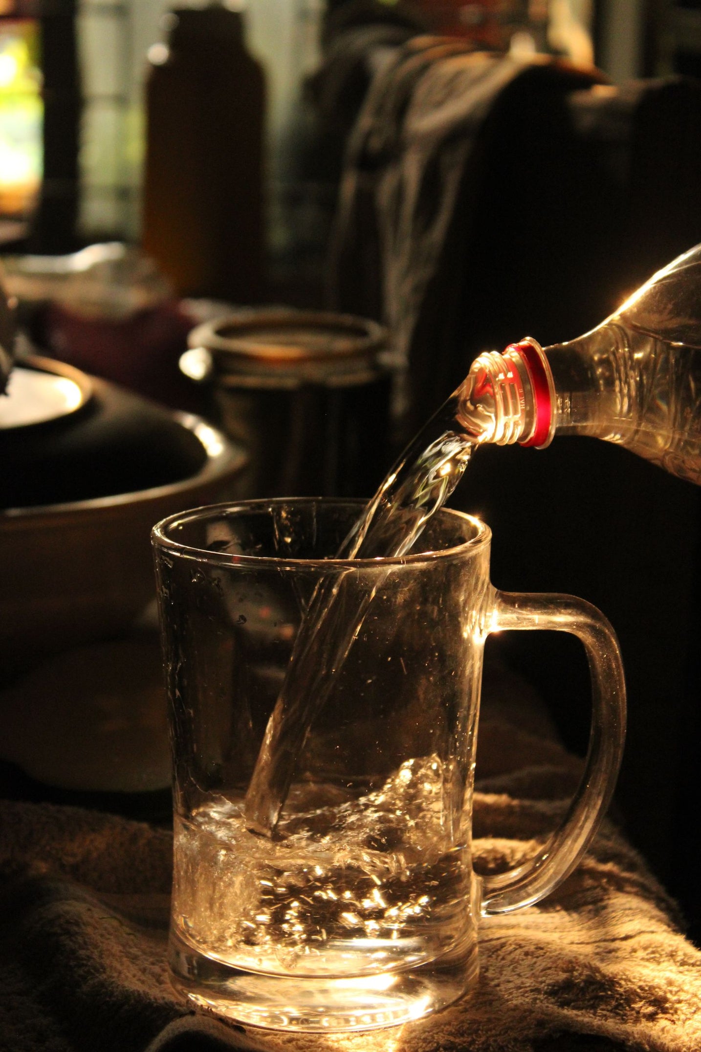 Fresh water poured into a glass mug in warm low light