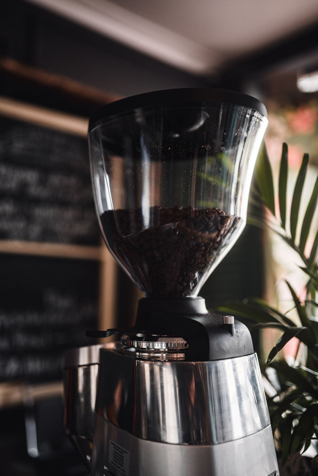Sleek electric burr grinder in a dim, cozy coffee bar