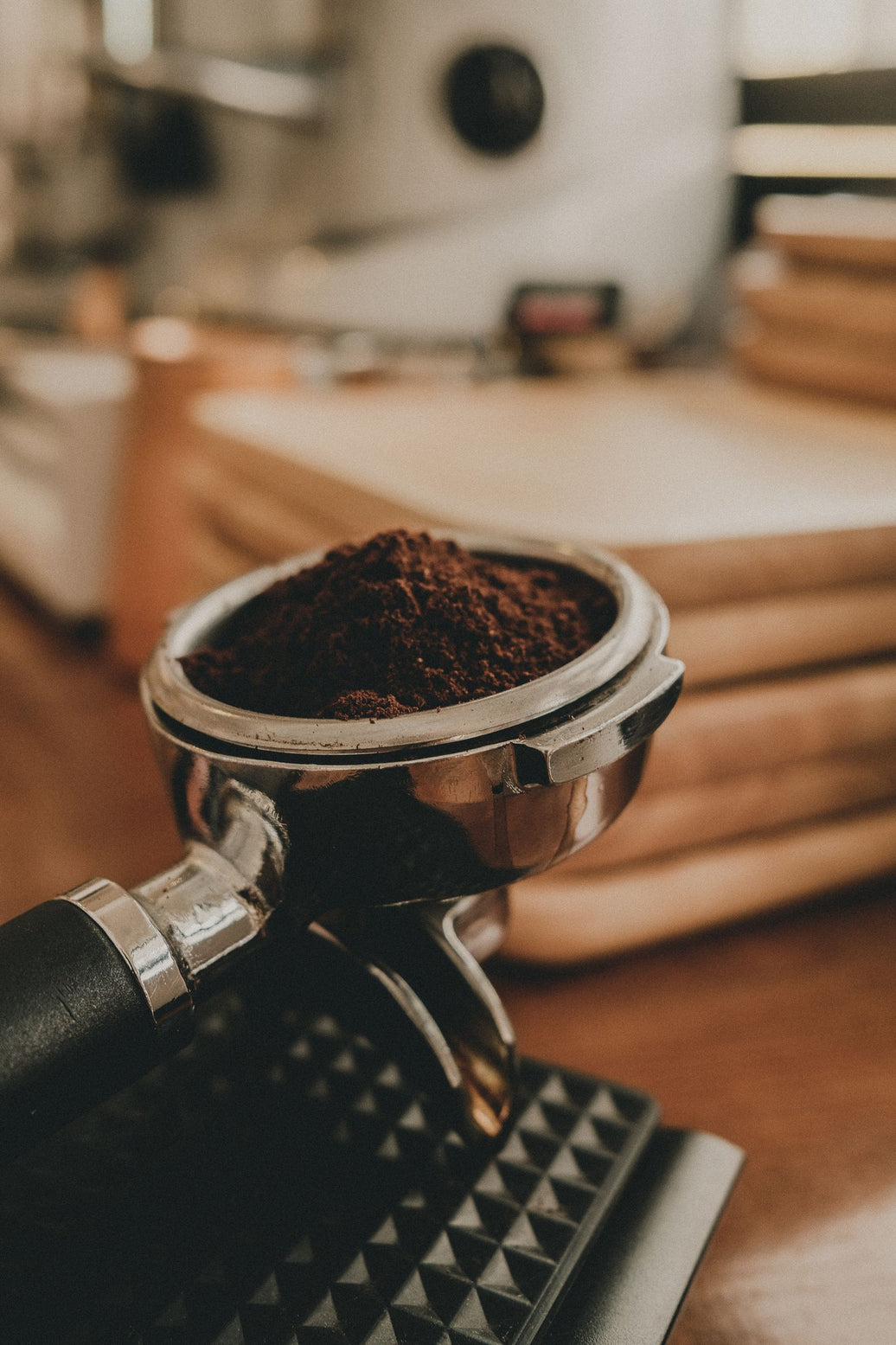 Portafilter filled with freshly ground espresso beside the grinder