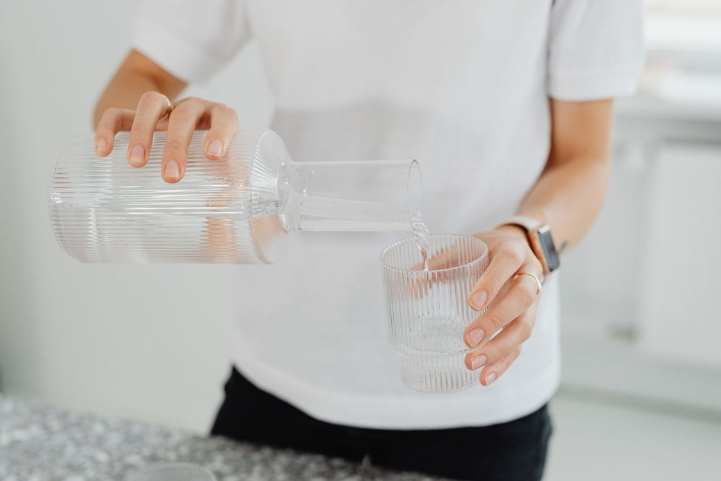 Clean water poured from a carafe into a clear glass