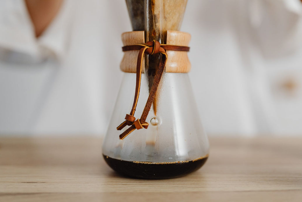 Chemex carafe of freshly brewed coffee on a warm wooden surface