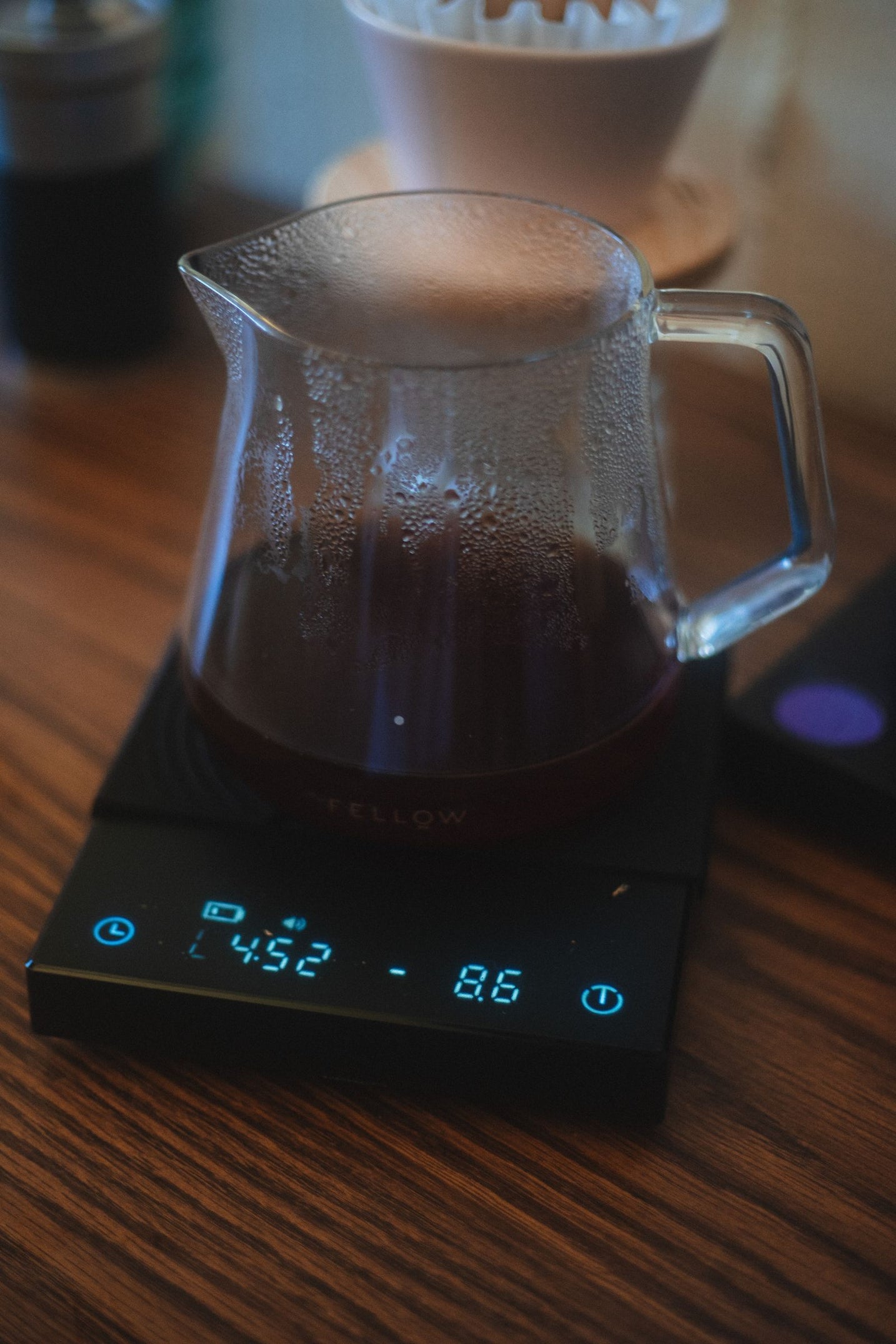 Digital coffee scale weighing a glass pot during a slow brew