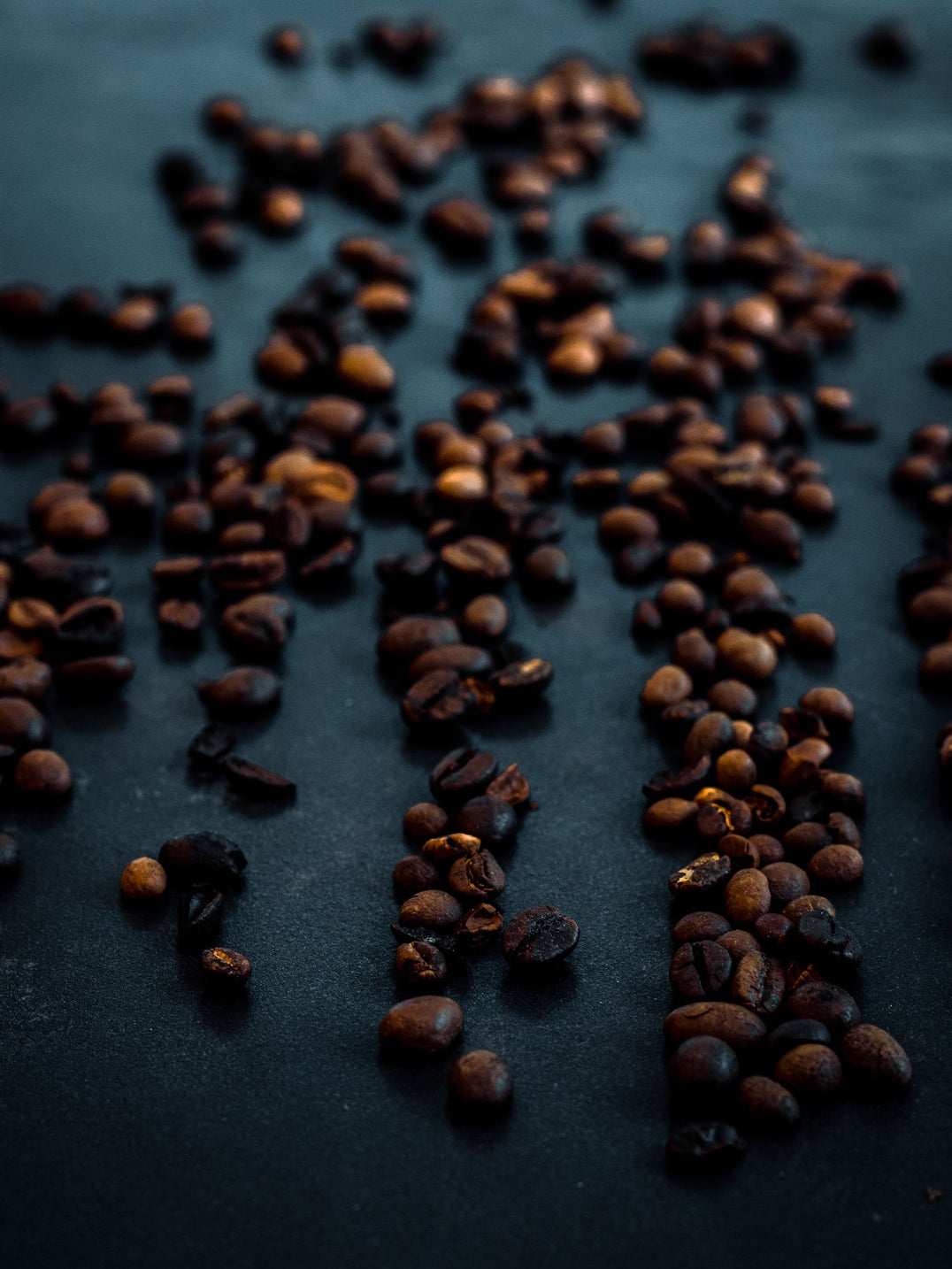 Roasted coffee beans scattered across a dark counter