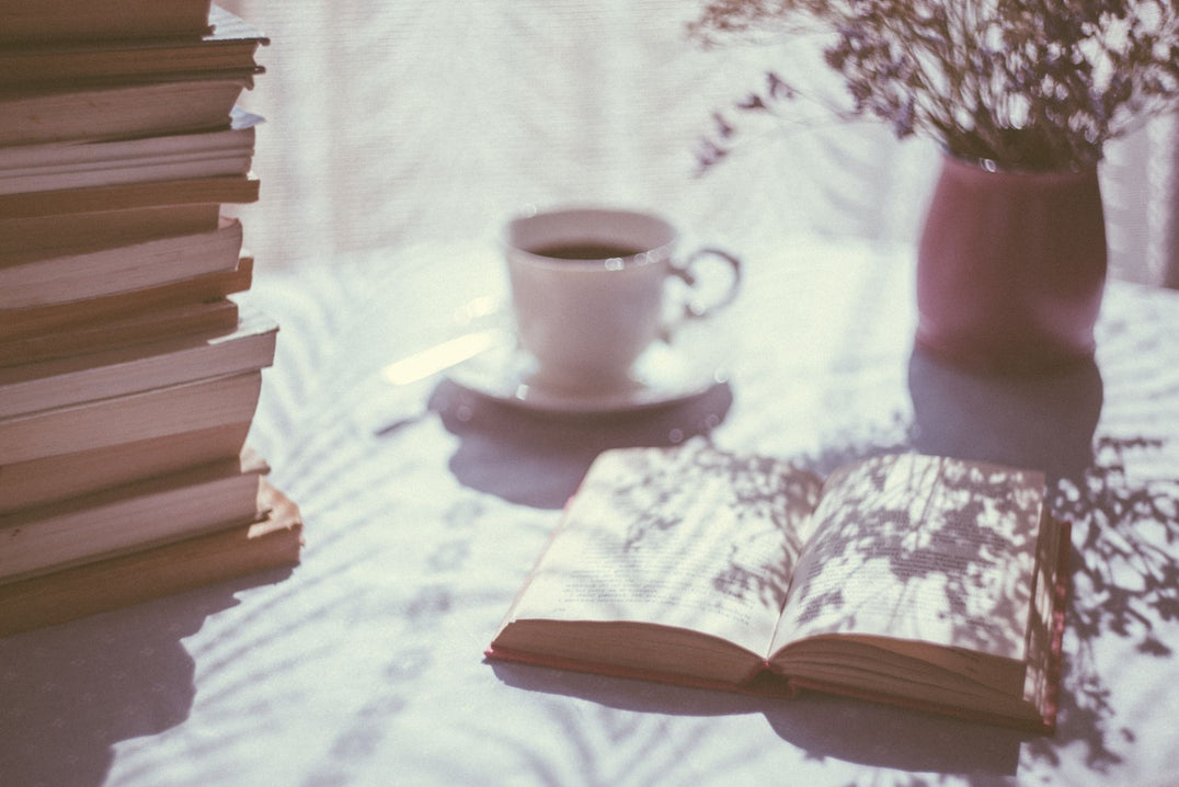 Opened book beside a ceramic coffee mug in moody warm light