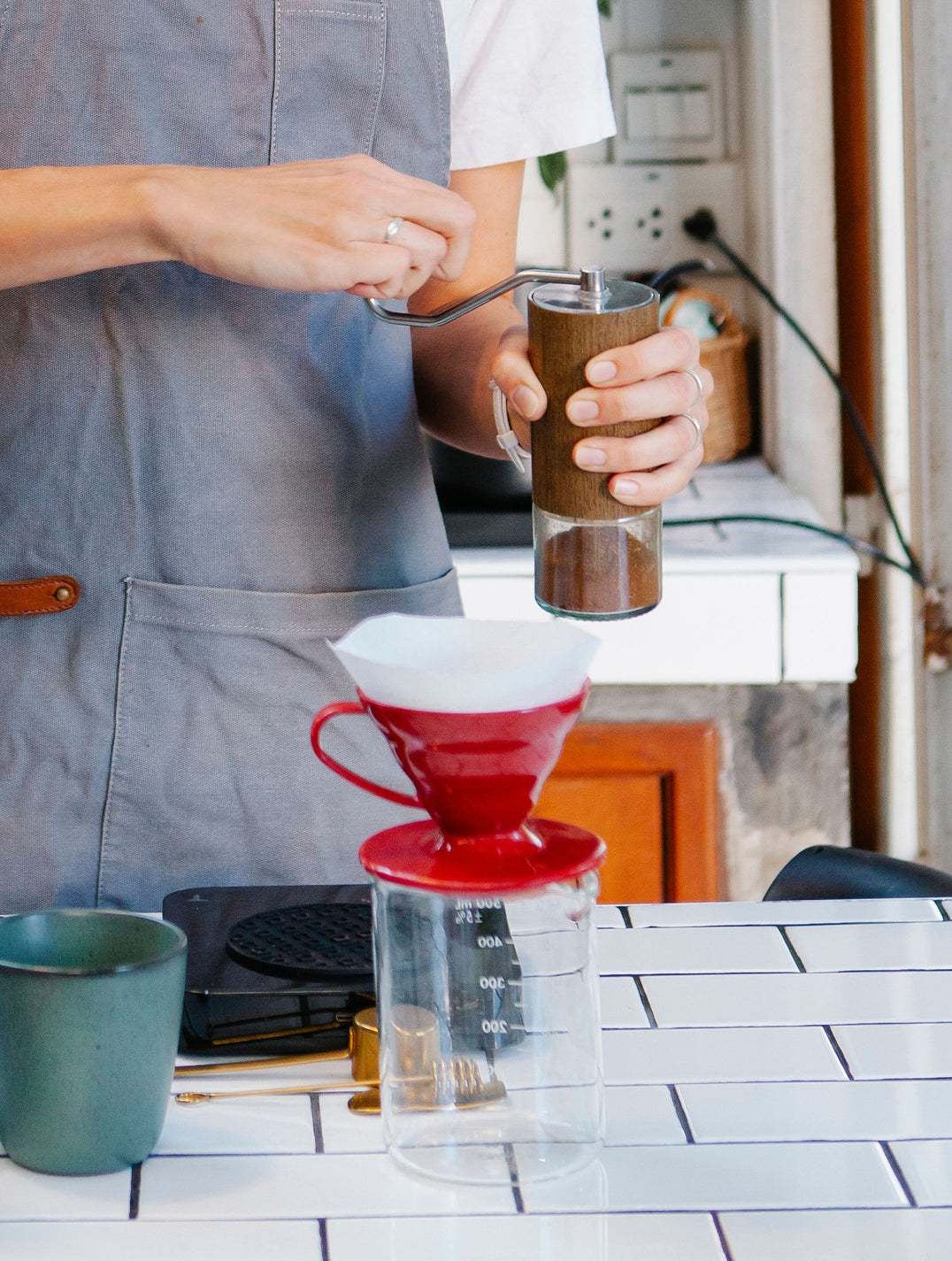 Hands grinding coffee beans with a manual burr grinder
